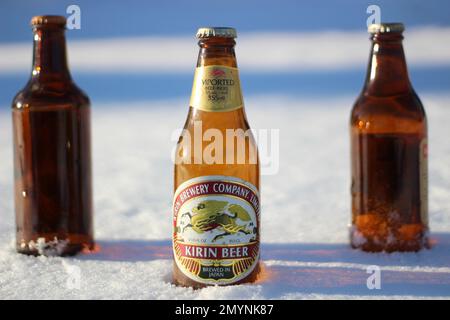 Three beer bottles in the snow, one old Japanese beer bottle in front. Stock Photo