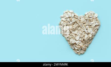 Dry rolled oatmeal cereal. An oat flakes with a heart or love shape on a pastel background with copy space. Stock Photo