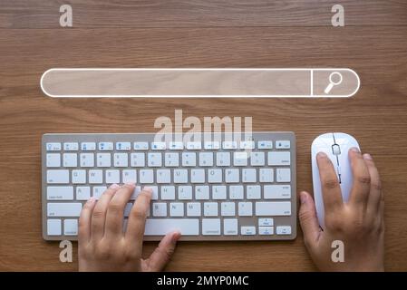 Hand holding mouse and computer keyboard with a search bar icon Stock Photo