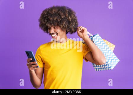 Smiley african man using the mobile while holing shopping bags Stock Photo