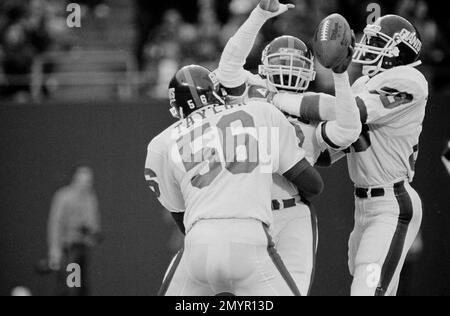 New York Giants' Mark Haynes, center, holds the ball aloft as he is hugged  by teammates Lawrence Taylor (56) and Perry Williams after Haynes  intercepted a Ken O'Brien pass on the goal line during fourth quarter  action at Giants Stadium in East Rutherfo