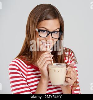 Love me some milkshake. Studio shot of an attractive young woman drinking a milkshake on a grey background. Stock Photo