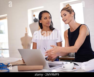 Discussing the new fashion trends. Two young fashion designers discussing a design. Stock Photo
