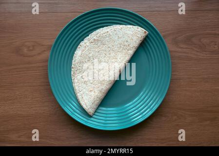 A folded wholegrain wrap on a green plate. Stock Photo