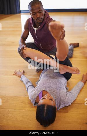 Helping to hone those stretching skills. a dance instructor helping his student to warm up in a dance. Stock Photo