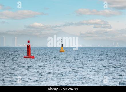 Marine red buoy in fairway. Navigational signs. Escorting ship to port. Floating yellow navigational buoy on blue sea. Marine signal buoy. Navigationa Stock Photo