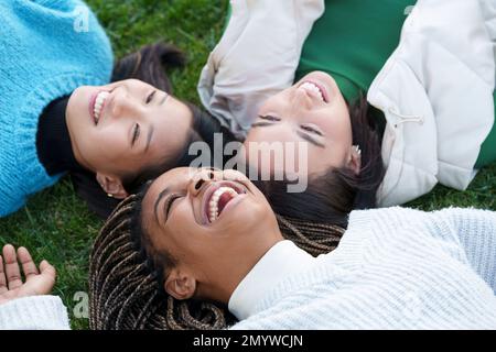 Three happy friends lying on the grass Stock Photo