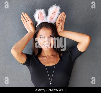 Im just a sweet little bunny. Portrait of a gorgeous brunette wearing bunny ears. Stock Photo