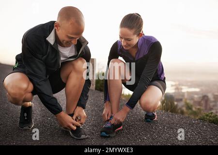 Readying for the run. a sporty couple stretching tying their shoelaces before a run. Stock Photo