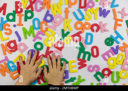 Young girl's hands sorting through Alphabet magnets on whiteboard Stock Photo