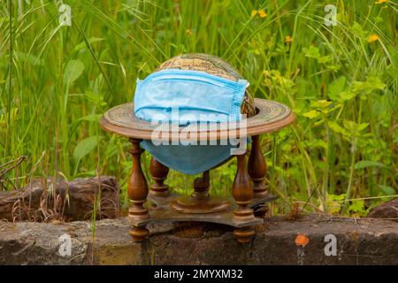 planet globe and medical mask lies on the grass on the street during a pandemic Stock Photo