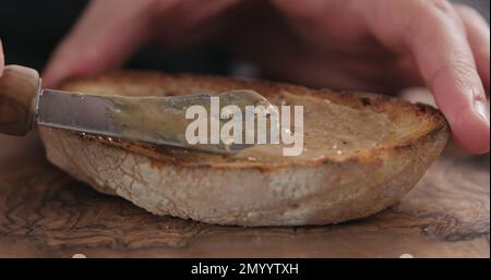 Spreading hazelnut spread on ciabatta slice, shallow focus Stock Photo