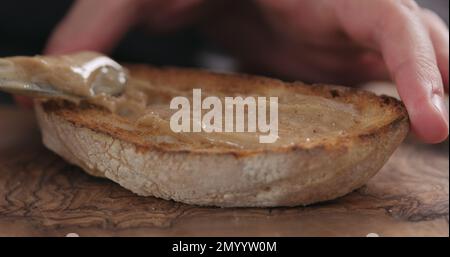 Spreading hazelnut spread on ciabatta slice, shallow focus Stock Photo