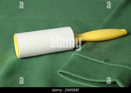 New lint roller with yellow handle on green sweatshirt Stock Photo