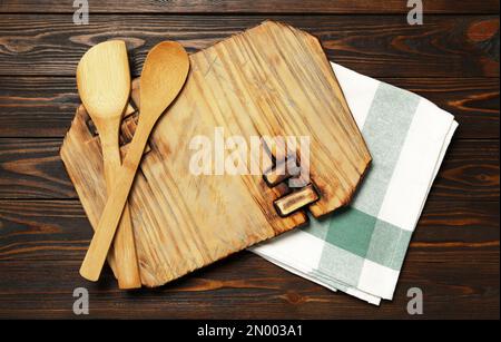 https://l450v.alamy.com/450v/2n003a1/board-spatula-and-spoon-with-towel-on-brown-wooden-table-flat-lay-cooking-utensils-2n003a1.jpg