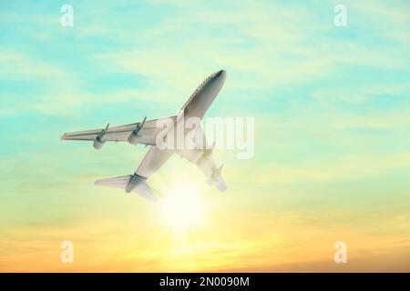 Airplane flying in sky at sunrise. Air transportation Stock Photo