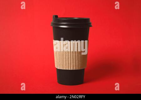 Takeaway paper coffee cup with cardboard sleeve on red background, closeup Stock Photo