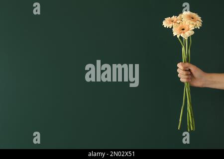 Woman holding beautiful bouquet near green chalkboard, space for text. Happy Teacher's Day Stock Photo