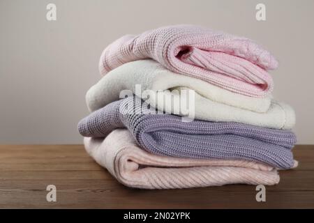 Stack of knitted sweaters on wooden table Stock Photo
