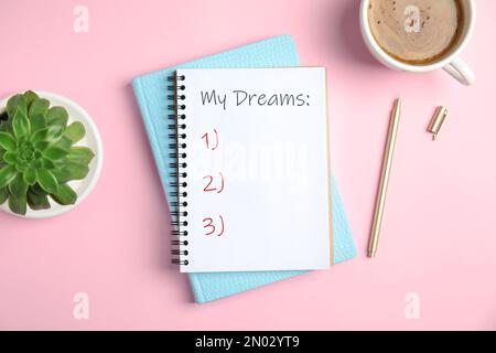 Notebook with dreams list on pink table, flat lay Stock Photo
