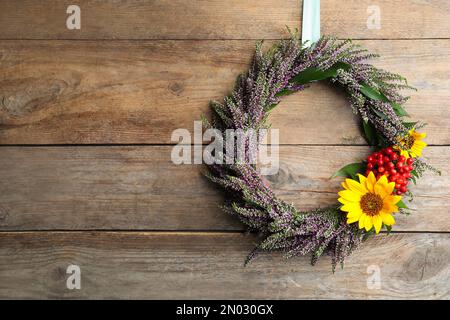 Beautiful autumnal wreath with heather flowers hanging on wooden background. Space for text Stock Photo
