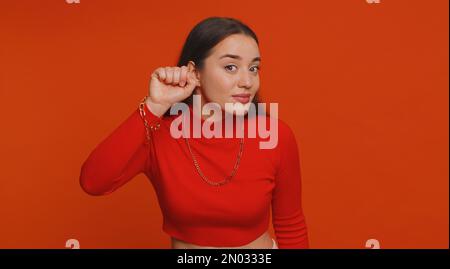 Knock-knock who is there, anybody home. Confused pretty woman knocking door gesture asking who is at home, feeling embarrassed, no idea, being clueless and uncertain. Young girl on gray background Stock Photo