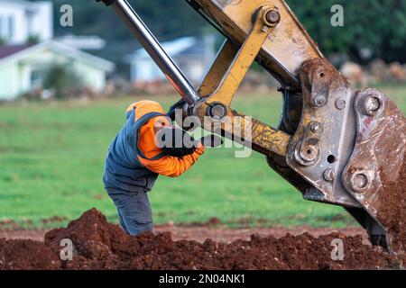 Excavator maintenance and repair operator doing repairs and maintenance. Stock Photo