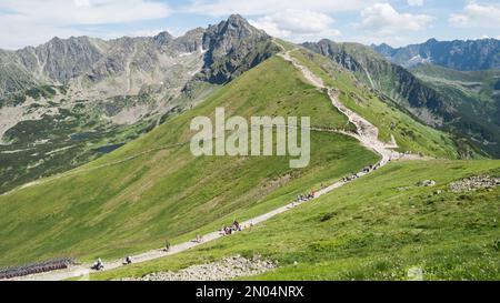Crowds of tourists walking on the trail towards a prominent mountain in the background, Poland, EU Stock Photo