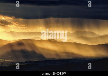 landscape with storm clouds and rainfall at the sunset over mountain range in Sicily, Italy Stock Photo