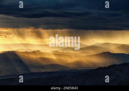 landscape with storm clouds and rainfall at the sunset over mountain range in Sicily, Italy Stock Photo