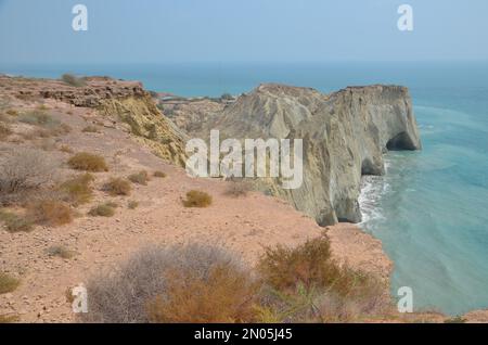 nice view to the Persian Gulf from a hill with some dry plants to the rock formation of Hormuz island, Iran Stock Photo