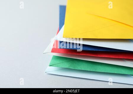 Stack of colorful paper envelopes on light background, closeup Stock Photo