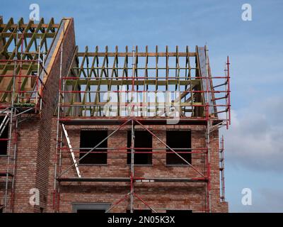 scaffolding against the facade of a new house and the framework of the roof Stock Photo