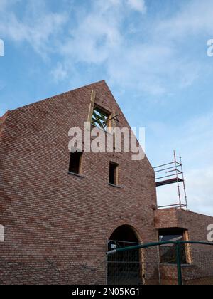 The side of an unfinished new building with scaffolding next to it Stock Photo