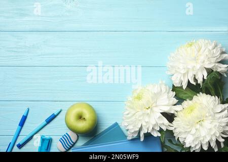 Flat lay composition with flowers, stationery and apple on light blue wooden background, space for text. Teacher's day Stock Photo