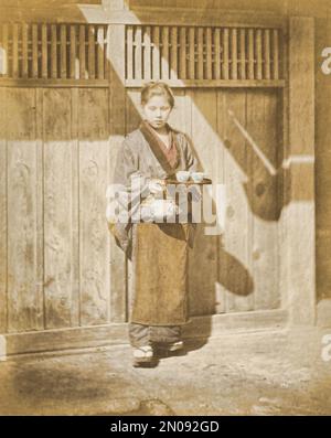 A photograph of a Japanese woman serving tea. Published in Views & Costumes of Japan by Stillfried and Andersen (Yokohama, 1877). Stock Photo