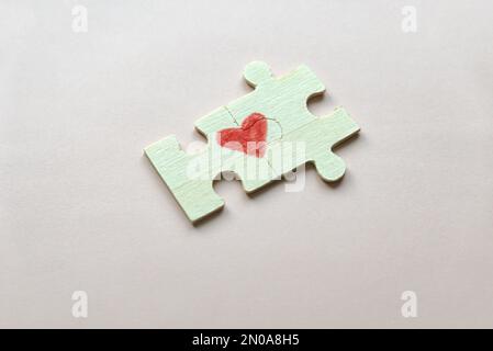 Selective focus of two pieces of a puzzle forming a heart on a pink background. Love concept. Stock Photo