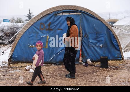 Rajo, Syria. 05th Feb, 2023. A Syrian woman stands with a child in front of their tent at a snow-covered camp for internally displaced Syrians near the city of Rajo in Aleppo. The refugee camps in northern Syria are under threat of extreme winter weather following heavy rain and snowfall in the previous days, worsening the plight of thousands of Syrian refugees. Credit: Anas Alkharboutli/dpa/Alamy Live News Stock Photo