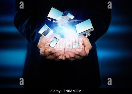 Young businessman holding different devices in hands on color background, closeup Stock Photo