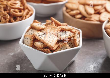 Delicious crackers in bowls on grey table, closeup Stock Photo