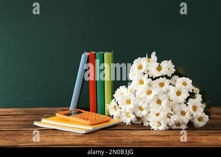 Set of stationery and flowers on wooden table near chalkboard. Teacher's Day Stock Photo
