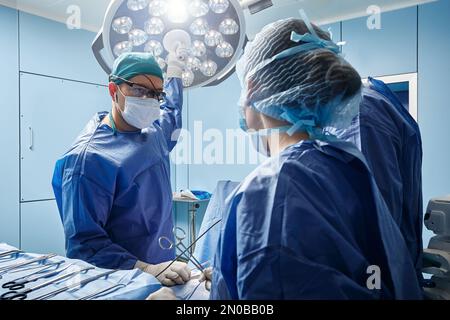Surgeons working on patient in modern operating room of hospital Stock Photo
