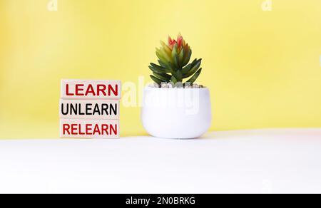 learn, unlearn, relearn - abstract words on wooden blocks with cactus flower and white and yellow background.Continuous learning, education and person Stock Photo