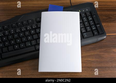 Blank white book cover template with blue bookmark on top of the black keyboard . Clipping path. Stock Photo