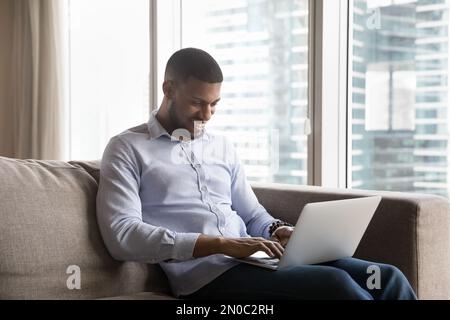Happy young Black freelance professional man typing on laptop Stock Photo