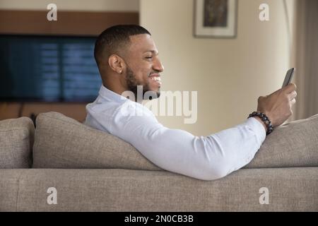 Cheerful excited handsome Black guy using mobile phone Stock Photo
