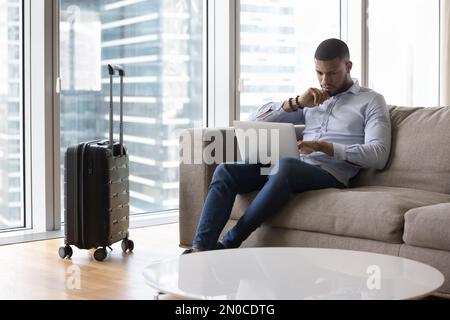 Serious pensive travelling freelance business man using laptop on sofa Stock Photo
