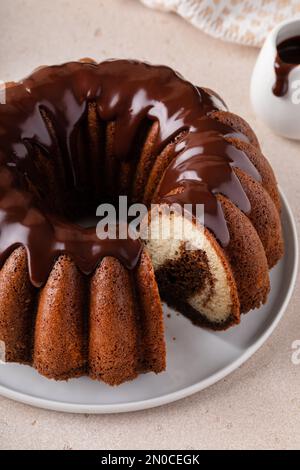 Chocolate marble bundt cake or zebra cake with chocolate glaze drizzled on top with a slice taken out Stock Photo