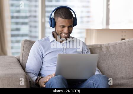Happy millennial Black freelancer man using laptop computer Stock Photo