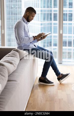 Focused young entrepreneur man using tablet at home Stock Photo